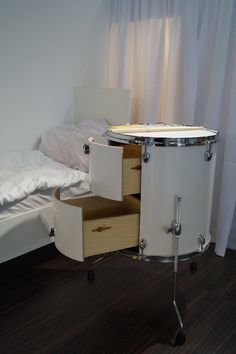 a white drum set sitting on top of a wooden floor next to a small bed