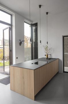 a kitchen with an island in the middle and glass doors leading to another room that has large windows