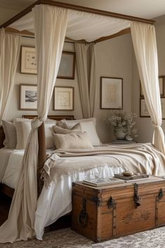 a bedroom with a canopy bed and white drapes on the ceiling, along with an antique trunk