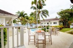 an outdoor dining area with tables and chairs next to a swimming pool in the background