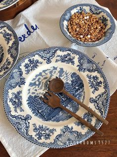 blue and white plates with wooden spoons on them sitting on top of a table