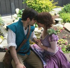 a man and woman dressed up as princesses sitting next to each other on a bench