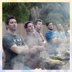 a group of men standing next to each other in front of grills with hot dogs on them