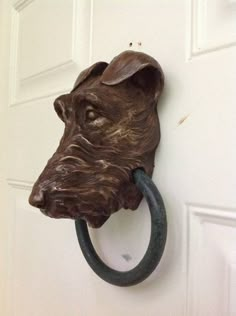 a door handle with a dog's head on it and a ring in front of the door