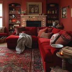 a living room with red couches, rugs and bookshelves in it