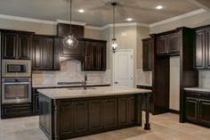 a large kitchen with dark wood cabinets and marble counter tops, along with an island in the middle