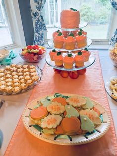 a table topped with cakes and cupcakes on top of plates next to a window