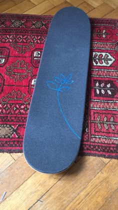 a blue skateboard sitting on top of a wooden floor next to a red rug