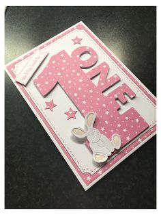 a pink and white greeting card with the number one on it's front corner