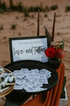 there is a sign that says love and tattoos next to some flowers on a table