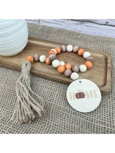 a bracelet with beads and tassels is sitting on a tray next to a bowl