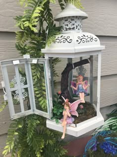 two fairy figurines sitting on top of a bird feeder