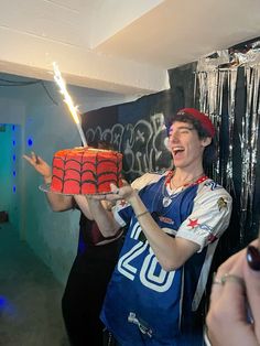 a man holding a cake with a spiderman on it and sparklers in the air