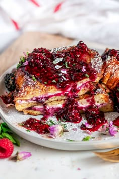 a white plate topped with french toast covered in raspberry sauce