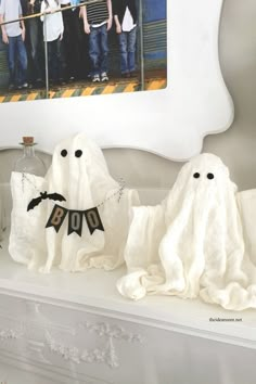 two ghost decorations on a mantle in front of a mirror