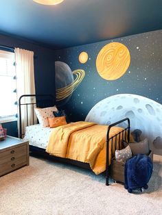 a child's bedroom decorated in blue, yellow and white with an outer space theme