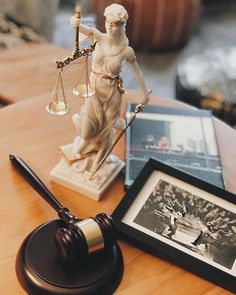 a statue of lady justice next to a judge's gavel on a table