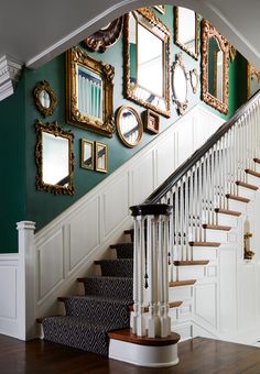 a staircase with mirrors on the wall and pictures on the wall above it in a home