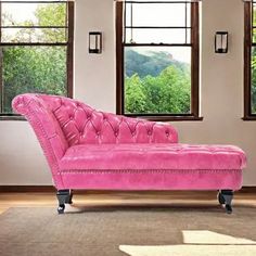 a pink couch sitting in front of three windows