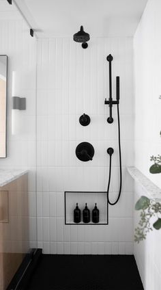 a black and white bathroom with shower head, soap dispenser, and mirror