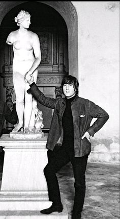 black and white photograph of two men standing in front of a statue with one holding the arm of another man's hand