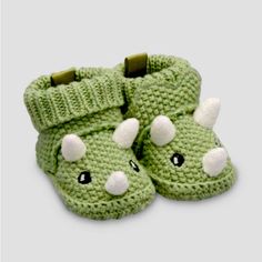 a pair of green crocheted slippers with white eyes and nose on them