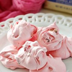 pink meringue on a white plate next to some yarn and a box of knitting needles