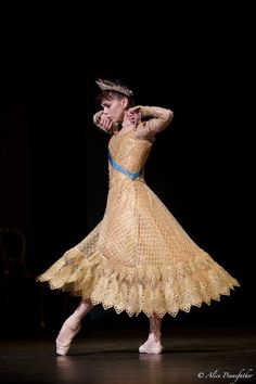 a woman in a yellow dress and tiara dancing with her hands behind her head