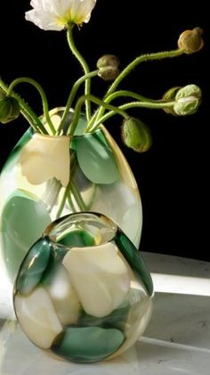 two vases with flowers in them sitting on a table