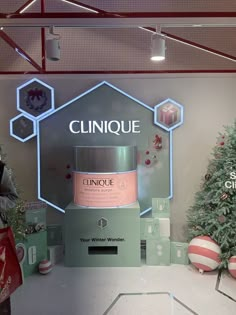 a display in a store with christmas decorations and lights on the wall, including a bottle of clinique