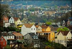 a city with lots of houses in the background and trees on the hill behind it