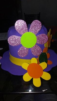 a purple hat with flowers on it sitting on top of a black table in the dark