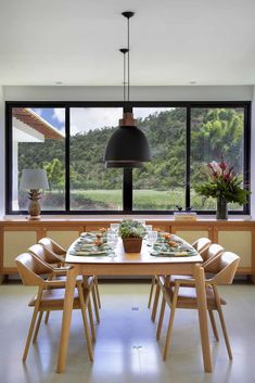 a dining room table and chairs in front of large windows