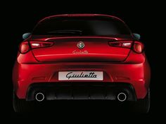 the rear end of a red alfa coupe in dark room with lights on and black background