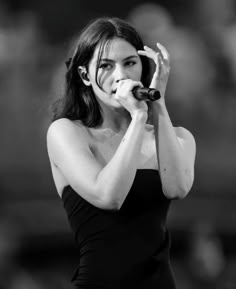 a black and white photo of a woman holding a microphone in her right hand while singing