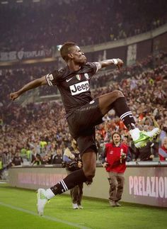 a man kicking a soccer ball on top of a field in front of a crowd