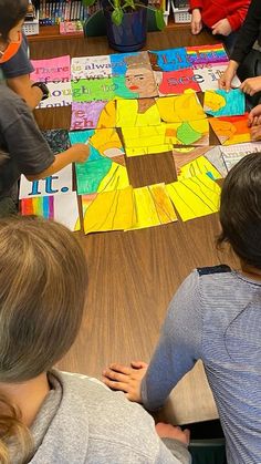 children are sitting at a table making artwork