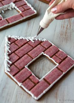 someone is decorating small gingerbread houses with icing