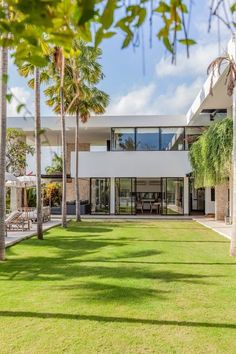 a house with palm trees in front of it and an open lawn area on the other side