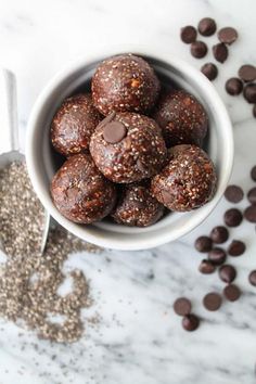 a white bowl filled with chocolate energy bites next to some chocolate chips and a spoon