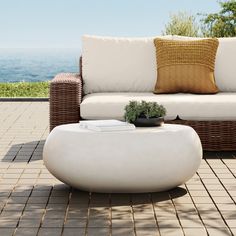 a white couch sitting on top of a patio next to a table with a potted plant