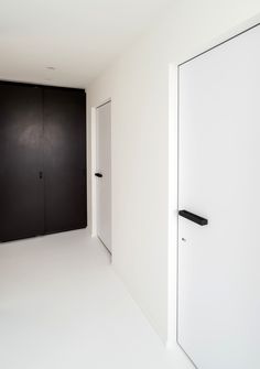 an empty room with black and white doors on the wall, and no one is in it