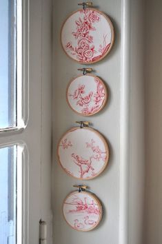 three embroidered wall hangings with flowers on them in front of a window sill