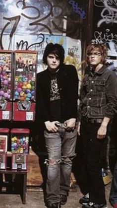 three young men standing in front of a store with graffiti on the walls and doors