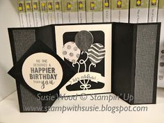 a birthday card with an envelope and balloons on the inside, sitting on a shelf in front of some books