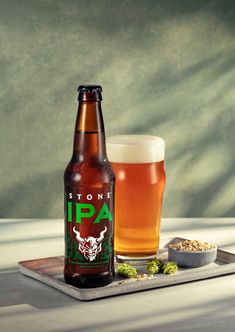 a bottle and glass sitting on top of a table next to a spoon filled with food