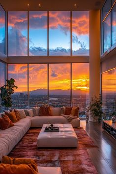 a living room filled with lots of furniture and large windows overlooking the city at sunset