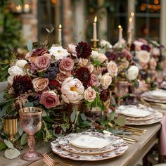 the table is set with plates and flowers in vases, candles, and napkins