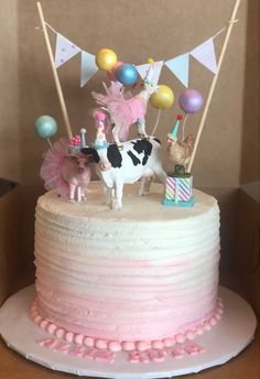 a birthday cake decorated with farm animals and balloons