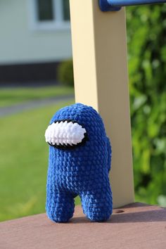 a blue stuffed animal with a white eye patch on it's face sitting next to a pole